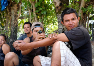 Migrantes se hacen tatuajes mientras esperan el tren en Chiapas, México, cerca de la frontera con Guatemala. Crédito de imagen: Jason De León