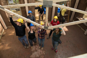 Los estudiantes levantan el techo del edificio de paja.