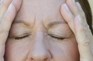 Mujer se toma la cabeza aparentemente sufriendo de dolor de cabeza.