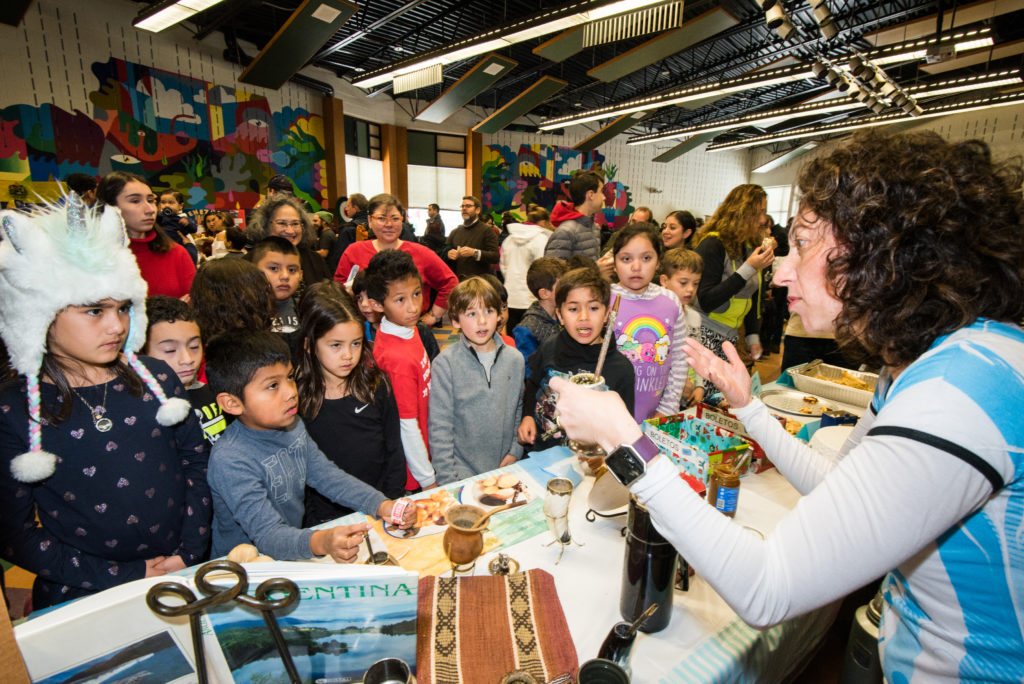 Estudiantes de En Nuestra Lengua pasan por las diferentes mesas en Bach Elementary durante la recaudación annual de fondos para el programa, que incluye la venta de comidas típicas de países de habla hispana.