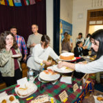 Padres y miembros de la comunidad participant en la recaudación annual de fondos para el programa En Nuestra Lengua, que incluye la venta de comidas típicas de países de habla hispana preparada por los mismos padres.