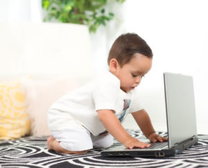 Un niño preescolar jugando con un computador.