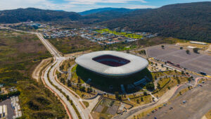 Vista aérea del Estadio Akron en Zapopan, Jalisco, rodeado de colinas y carreteras; el estadio es una sede confirmada para la Copa Mundial de la FIFA 2026.