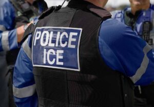 Inscripción “POLICE ICE” en la parte posterior de un chaleco antibalas resistente a puñaladas usado por un grupo de tres agentes de policía. Crédito de la imagen: Adobe Stock.